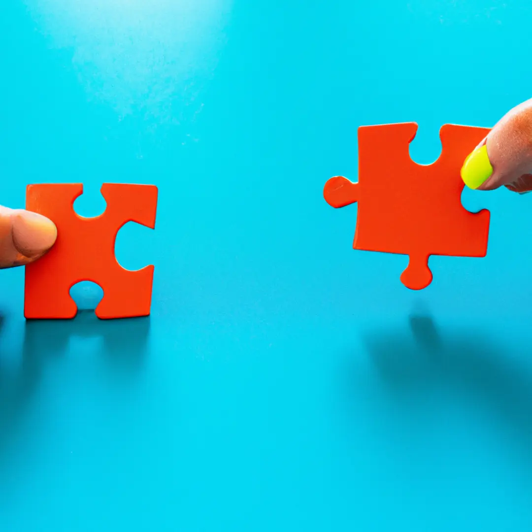 Two interconnected puzzle pieces symbolizing a business partnership, representing growth and access to new customers.