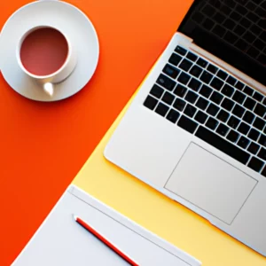 A flat lay image of a laptop, notebook, pen, and a cup of coffee on a desk.