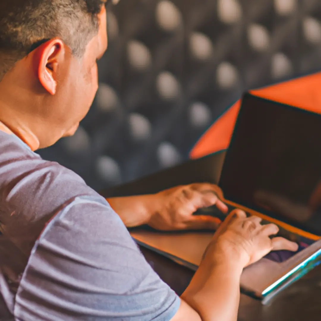 A small business owner writing a blog article on a laptop.